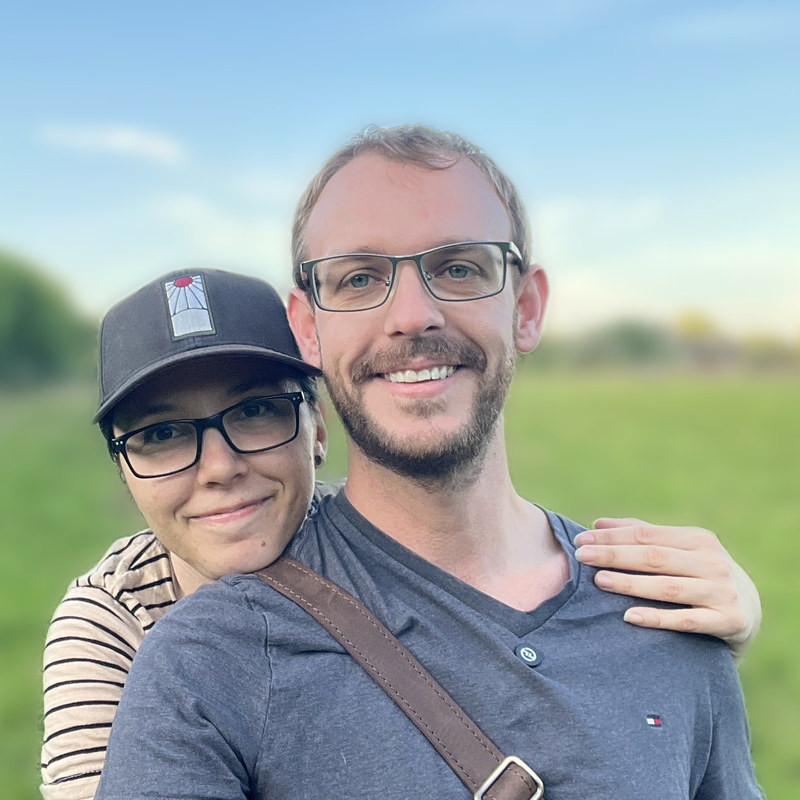 Cassidy and his wife together in a green field at golden hour.